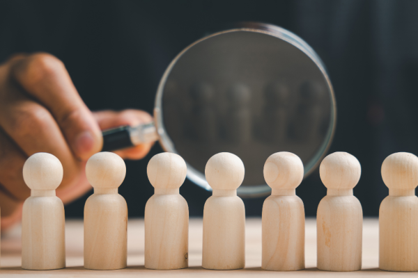 A magnifying glass focuses on a row of small wooden pegs that represent the population